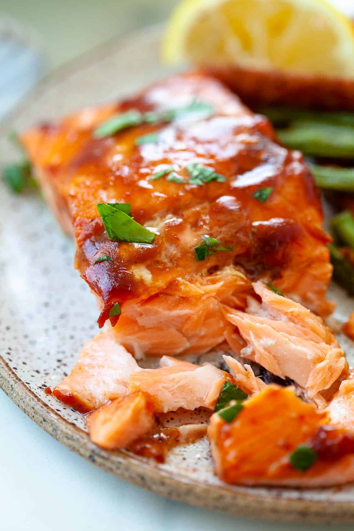 close up. bbq salmon. saucy. flaked. cilantro. lemon wedge.