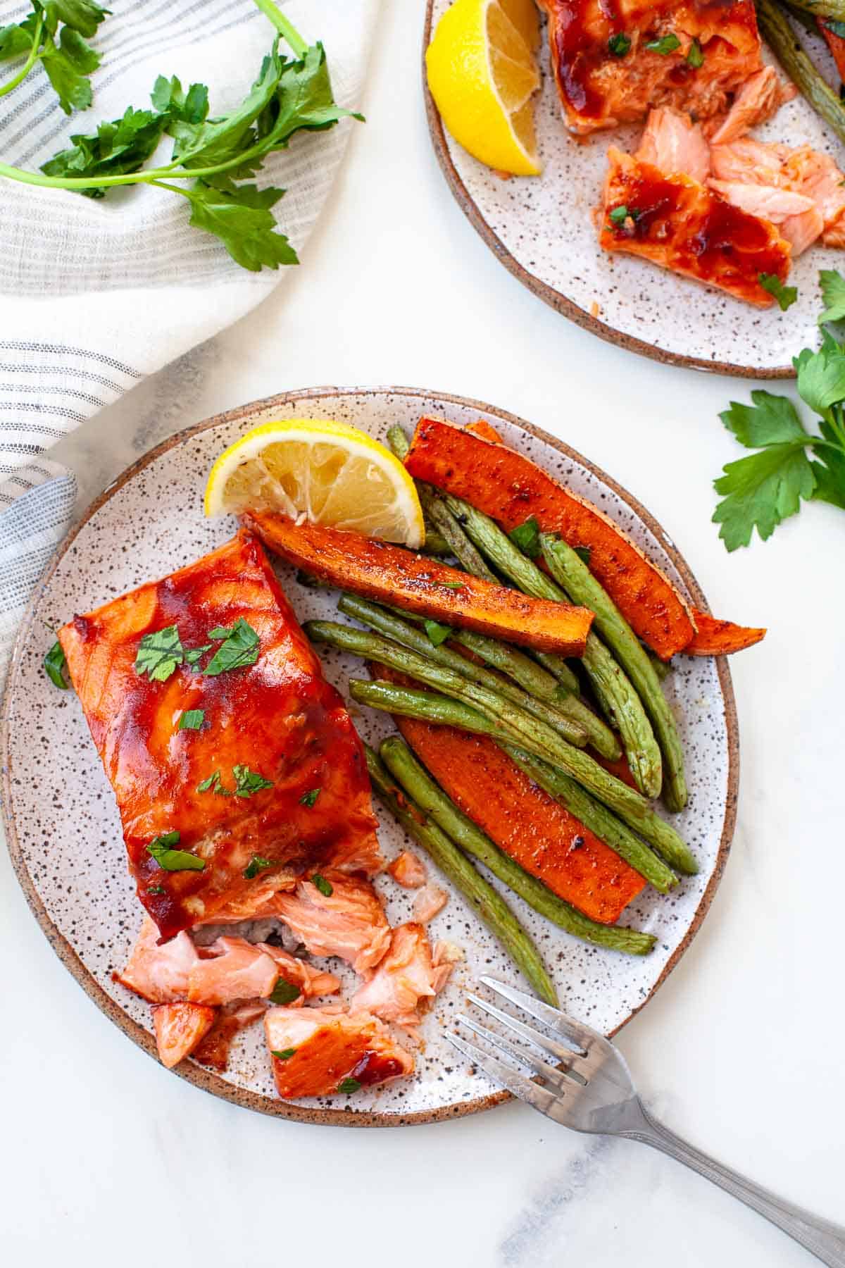 bbq salmon. flaked. green beans. sweet potato. lemon slice. on grey plate. sprigs of cilantro. 