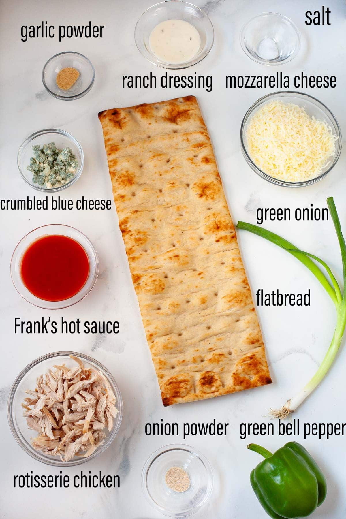 ingredients for buffalo chicken flatbread laid on marble surface with black text overlay for each